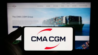 Stuttgart, Almanya - 08-13-2023: Fransız lojistik şirketi CMA CGM S.A. 'nın logosuna sahip akıllı telefon sahibi kişi web sitesinin önünde ekranda. Telefon ekranına odaklan.