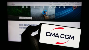 Stuttgart, Almanya - 08-13-2023: Fransız lojistik şirketi CMA CGM SA 'nın logosuna sahip cep telefonu sahibi kişi iş sayfasının önünde ekranda. Telefon ekranına odaklan.