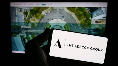 Stuttgart, Almanya - 08-13-2023: İnsan kaynakları şirketi The Adecco Group AG 'nin logosunu taşıyan kişi web sitesinin önünde ekranda. Telefon ekranına odaklan.