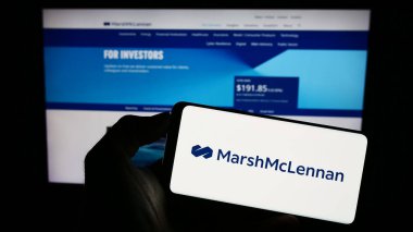 Stuttgart, Almanya - 08-14-2023: Amerikan Marsh McLennan şirketinin logosunun bulunduğu cep telefonu sahibi kişi web sayfasının önünde ekranda. Telefon ekranına odaklan.