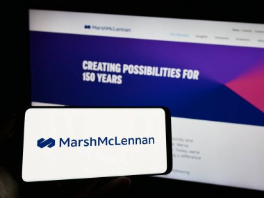 Stuttgart, Almanya - 08-14-2023: ABD 'li Marsh McLennan Company Inc.' nin logosuyla cep telefonu sahibi kişi iş sayfası önünde ekranda. Telefon ekranına odaklan.