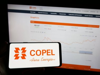 Stuttgart, Almanya - 08-14-2023: İnternet sayfası önünde üzerinde Companhia Paranaense de Energia (Copel) şirketinin logosu bulunan cep telefonu sahibi kişi. Telefon ekranına odaklan.
