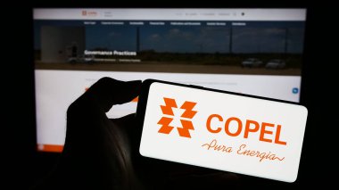 Stuttgart, Germany - 08-14-2023: Person holding cellphone with logo of company Companhia Paranaense de Energia (Copel) on screen in front of webpage. Focus on phone display. clipart