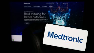 Stuttgart, Almanya - 08-14-2023: Web sitesinin önünde ekranda tıbbi teknoloji şirketi Medtronic plc 'nin logosuna sahip akıllı telefonu tutan kişi. Telefon ekranına odaklan.