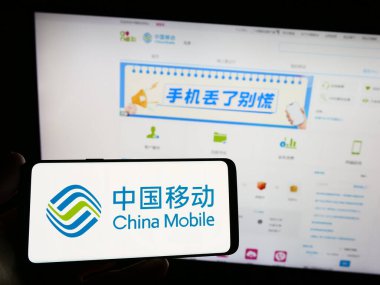 Stuttgart, Almanya - 08-14-2023: Telekomünikasyon şirketi China Mobile Limited 'in logosuna sahip akıllı telefon sahibi kişi web sitesi önünde ekranda. Telefon ekranına odaklan.