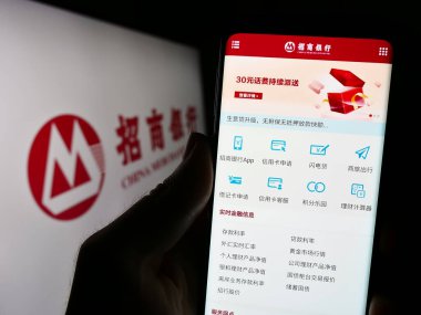 Stuttgart, Almanya - 08-14-2023: Çinli Merchants Bank Limited (CMB) şirketinin web sitesi olan cep telefonu logosu önünde ekranda. Telefon ekranının merkezine odaklan.