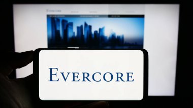 Stuttgart, Almanya - 08-14-2023: ABD 'li yatırım bankası Evercore Inc.' in logosuyla cep telefonu sahibi kişi iş sayfasının önünde ekranda. Telefon ekranına odaklan.