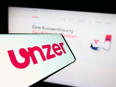 Stuttgart, Almanya - 08-15-2023: Alman ödeme şirketi Unzer GmbH 'nin logosunun yer aldığı cep telefonu iş sitesinin önünde ekranda. Telefon ekranının merkez soluna odaklan.