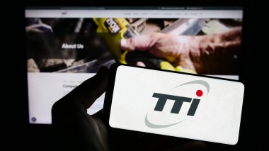 Stuttgart, Almanya - 08-15-2023: İnternet sitesi önünde üzerinde Techtronic Industries Limited (TTI) logosu olan akıllı telefon sahibi kişi. Telefon ekranına odaklan.