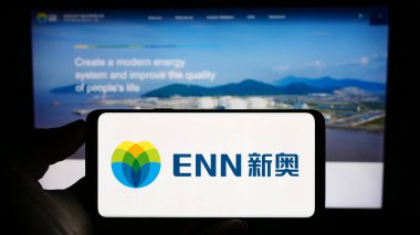 Stuttgart, Almanya - 08-16-2023: Çinli şirket ENN Energy Holding Limited 'in logosuyla cep telefonu sahibi kişi iş sayfasının önünde ekranda görülüyor. Telefon ekranına odaklan.
