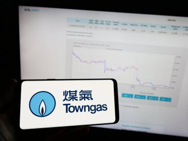 Stuttgart, Almanya - 08-16-2023: İnternet sayfasının önünde üzerinde The Hong Kong and China Gas Co. Ltd. (Towngas) logosu bulunan kişi. Telefon ekranına odaklan.