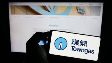 Stuttgart, Almanya - 08-16-2023: İnternet sitesinin önünde üzerinde The Hong Kong and China Gas Co. Ltd. (Towngas) logosu bulunan kişi. Telefon ekranına odaklan.