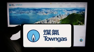 Stuttgart, Almanya - 08-16-2023: İnternet sayfasının önünde üzerinde The Hong Kong and China Gas Co. Ltd. (Towngas) logosu bulunan kişi. Telefon ekranına odaklan.
