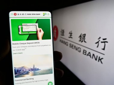 Stuttgart, Almanya - 08-16-2023: Çinli şirket Hang Seng Bank Limited 'in internet sayfası olan cep telefonu logosu önünde ekranda. Telefon ekranının merkezine odaklan.