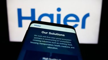 Stuttgart, Almanya - 08-17-2023: Ev aletleri şirketi Haier Group Corporation 'ın web sitesi olan akıllı telefon logonun önünde ekranda. Telefon ekranının sol üst kısmına odaklan.