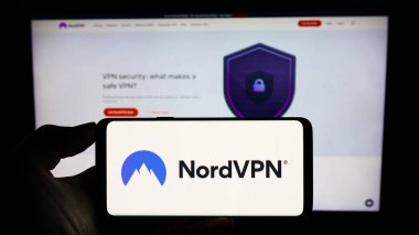 Stuttgart, Almanya - 08-17-2023: İş sayfası önünde VPN servisi NordVPN (Nordsec Ltd.) logosu olan cep telefonu sahibi kişi. Telefon ekranına odaklan.