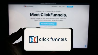 Stuttgart, Almanya - 08-17-2023: İnternet sitesinin önünde üzerinde ClickFunnels (Etison LLC) yazılım şirketinin logosu bulunan akıllı telefon sahibi kişi. Telefon ekranına odaklan.