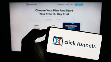Stuttgart, Almanya - 08-17-2023: Yazılım şirketi ClickFunnels (Etison LLC) logosuna sahip cep telefonu sahibi kişi iş sayfası önünde ekranda. Telefon ekranına odaklan.