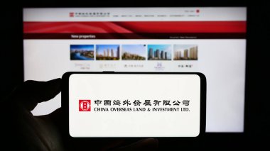 Stuttgart, Almanya - 08-17-2023: İnternet sayfası önünde üzerinde Çin Denizaşırı Topraklar ve Yatırım Limited (COLI) logosu bulunan kişi. Telefon ekranına odaklan.