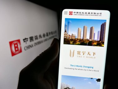 Stuttgart, Almanya - 08-17-2023: Çin Denizaşırı Topraklar ve Yatırım Limited 'in (COLI) web sayfası logolu cep telefonu tutan kişi. Telefon ekranının merkezine odaklan.