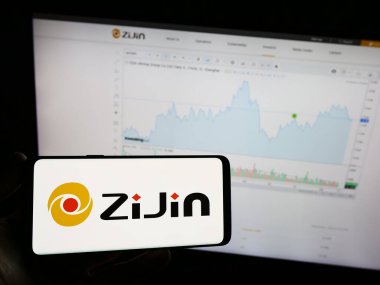 Stuttgart, Almanya - 08-17-2023: Çinli şirket Zijin Mining Group Co. 'nun logosunun bulunduğu cep telefonu sahibi kişi web sayfası önünde ekranda sınırlı. Telefon ekranına odaklan.