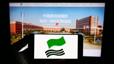 Stuttgart, Almanya - 08-17-2023: Shenzhou International Group Holding Limited logosuna sahip akıllı telefon sahibi kişi web sitesi önünde ekranda görülüyor. Telefon ekranına odaklan.