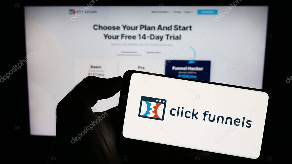 Stuttgart, Germany - 08-17-2023: Person holding cellphone with logo of software company ClickFunnels (Etison LLC) on screen in front of business webpage. Focus on phone display.