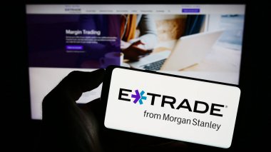 Stuttgart, Almanya - 08-20-2023: ABD 'li E-Trade Financial Corporation şirketinin logosuyla cep telefonu sahibi kişi iş sayfasının önünde ekranda. Telefon ekranına odaklan.
