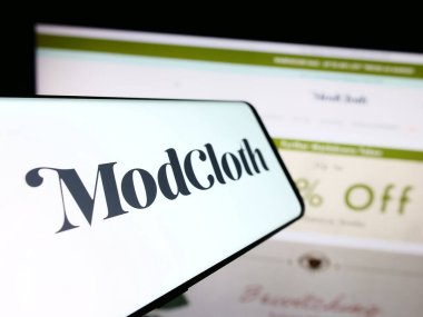 Stuttgart, Germany - 08-20-2023: Cellphone with logo of American e-commerce company ModCloth on screen in front of business website. Focus on center-left of phone display. clipart