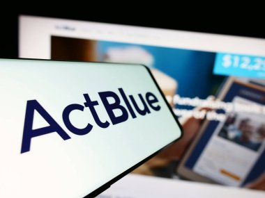 Stuttgart, Germany - 08-20-2023: Mobile phone with logo of fundraising organization ActBlue Charities Inc. on screen in front of website. Focus on center-left of phone display. clipart