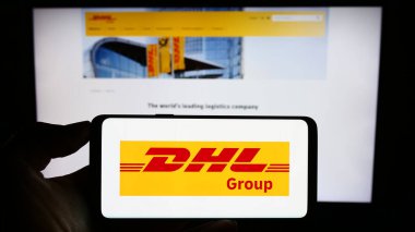 Stuttgart, Almanya - 08-20-2023: İnternet sitesi önünde üzerinde lojistik şirketi Deutsche Post (DHL Group) logosu bulunan akıllı telefon sahibi kişi. Telefon ekranına odaklan.
