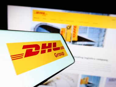 Stuttgart, Almanya - 08-20-2023: Lojistik şirketi Deutsche Post 'un logosuna sahip akıllı telefon (DHL Group) web sitesinin önünde ekranda. Telefon ekranının merkez soluna odaklan.