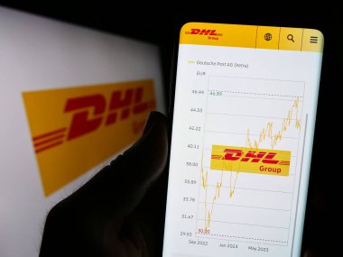 Stuttgart, Almanya - 08-20-2023: Lojistik şirketi Deutsche Post 'un (DHL Group) web sayfası logolu cep telefonu tutan kişi. Telefon ekranının merkezine odaklan.