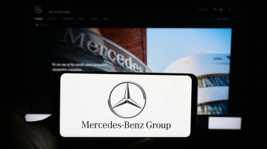 Stuttgart, Almanya - 08-20-2023: Otomotiv şirketi Mercedes-Benz Group AG 'nin logolu cep telefonu iş sayfasının önünde ekranda. Telefon ekranına odaklan.