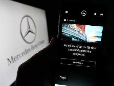 Stuttgart, Almanya - 08-20-2023: Otomotiv şirketi Mercedes-Benz Group AG 'nin web sayfası olan cep telefonu logonun önünde ekranda. Telefon ekranının merkezine odaklan.