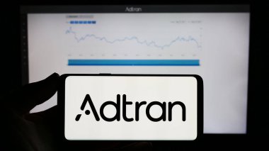 Stuttgart, Almanya - 08-20-2023: Web sayfası önünde ekranda ABD 'li telekomünikasyon şirketi Adtran Inc.' in logosunun bulunduğu cep telefonu sahibi kişi. Telefon ekranına odaklan.