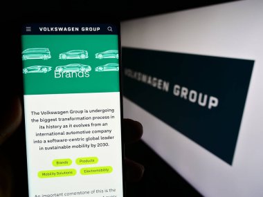 Stuttgart, Almanya - 08-20-2023: Alman otomotiv şirketi Volkswagen AG 'nin web sayfası olan akıllı telefon sahibi kişi logonun önünde ekranda. Telefon ekranının merkezine odaklan.