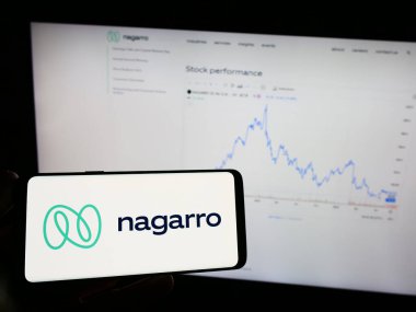 Stuttgart, Almanya - 08-20-2023: Bilgi teknolojisi şirketi Nagarro SE 'nin logosuyla cep telefonu sahibi kişi iş sayfasının önünde ekranda. Telefon ekranına odaklan.