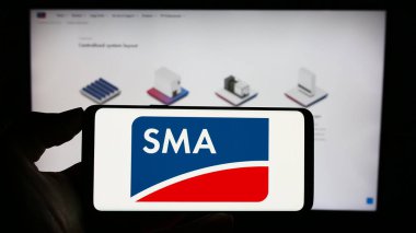 Stuttgart, Almanya - 08-21-2023: Alman firması SMA Solar Technology AG 'nin logosuyla cep telefonu sahibi kişi iş sayfasının önünde ekranda görülüyor. Telefon ekranına odaklan.