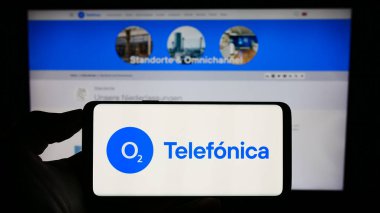 Stuttgart, Almanya - 08-21-2023: Telefica Deutschland Holding AG şirketinin logosuna sahip akıllı telefon sahibi kişi web sitesi önünde ekranda görülüyor. Telefon ekranına odaklan.