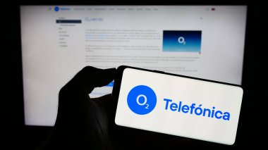 Stuttgart, Almanya - 08-21-2023: Telefica Deutschland Holding AG şirketinin logosuyla cep telefonu sahibi kişi iş sayfasının önünde ekranda görülüyor. Telefon ekranına odaklan.