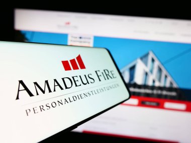 Stuttgart, Almanya - 08-21-2023: Alman işe alım şirketi Amadeus FiRe AG 'nin logosunun yer aldığı cep telefonu web sitesinin önünde ekranda. Telefon ekranının merkez soluna odaklan.