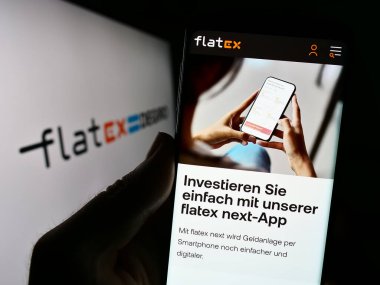 Stuttgart, Almanya - 08-21-2023: Alman fintech şirketi Flatexdegiro AG 'nin web sitesi ile logo önünde akıllı telefon tutan kişi. Telefon ekranının merkezine odaklan.