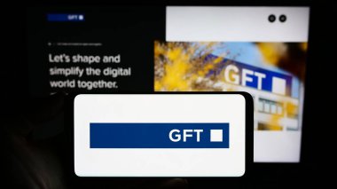 Stuttgart, Almanya - 08-21-2023: İnternet sitesi önünde üzerinde Alman bilişim şirketi GFT Technologies SE 'nin logosu olan akıllı telefonu tutan kişi. Telefon ekranına odaklan.