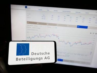 Stuttgart, Almanya - 08-21-2023: Alman Deutsche Beteiligungs AG (DBAG) logosuna sahip cep telefonu sahibi kişi web sayfası önünde ekranda. Telefon ekranına odaklan.
