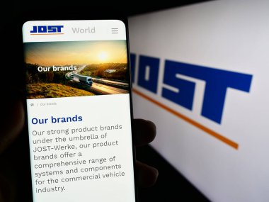 Stuttgart, Almanya - 08-22-2023: Alman otomotiv şirketi Jost Werke SE 'nin web sayfası ile akıllı telefon sahibi kişi logonun önünde ekranda. Telefon ekranının merkezine odaklan.