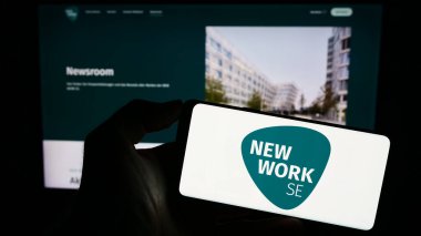 Stuttgart, Almanya - 08-22-2023: Alman firması New Work SE 'nin (XING) logosuyla cep telefonu sahibi kişi iş sayfası önünde ekranda. Telefon ekranına odaklan.