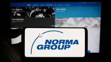 Stuttgart, Almanya - 08-22-2023: Alman imalat şirketi Norma Group SE 'nin logosuyla cep telefonu sahibi kişi iş sayfasının önünde ekranda. Telefon ekranına odaklan.