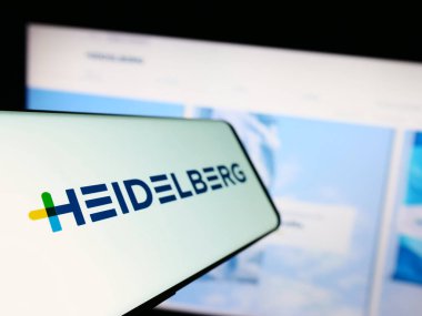 Stuttgart, Almanya - 08-22-2023: Alman şirketi Heidelberger Druckmaschinen AG 'nin logosunu taşıyan akıllı telefon iş sitesinin önünde ekranda. Telefon ekranının soluna odaklan.