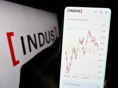 Stuttgart, Almanya - 08-22-2023: Alman yatırım şirketi INDUS Holding AG 'nin web sitesi ile akıllı telefon sahibi kişi logonun önünde ekranda. Telefon ekranının merkezine odaklan.